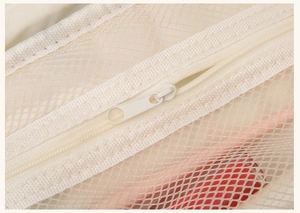 Detail of a creamy white mesh wash bag showing zipper closure and breathable translucent texture