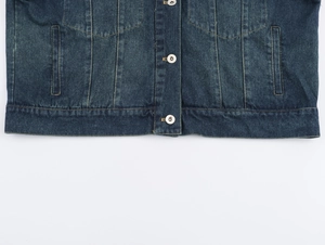 Détail de l'ourlet de la veste en jean bleu foncé et boutons métalliques de qualité