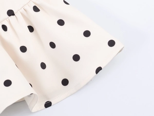 Macro shot of white fabric with black polka dots and detailed ruffled hem stitching