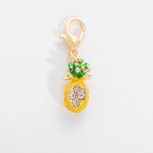 Close-up of a gold pineapple charm with yellow enamel and sparkling crystal accents