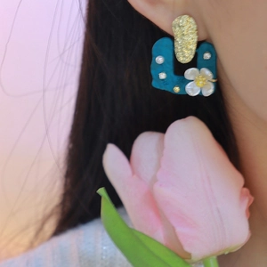 Blue square floral earrings with pearls and gold texture worn by a female model