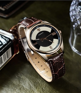 Close-up of gold watch with leather strap and dual-tone dial against a lifestyle background