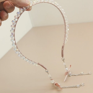 Detail of pink crystal beaded headband featuring silver chain tassels and bow accents