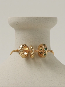 Vintage gold necklace with emerald green charms displayed on a ceramic vase