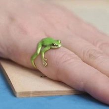 Primer plano detallado de un anillo de rana verde realista usado en el dedo de una mujer