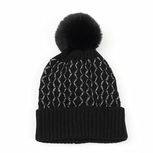 Detailed view of black knit beanie with silver metallic thread and faux fur pompom