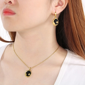 Model wearing stainless steel jewelry set with black enamel star and moon round pendants