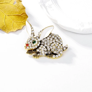 Sparkling crystal rabbit brooch with green eyes and red nose on elegant gold leaf background