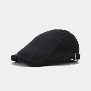 Close-up of black cotton twill beret with adjustable metal side buckle and textured fabric