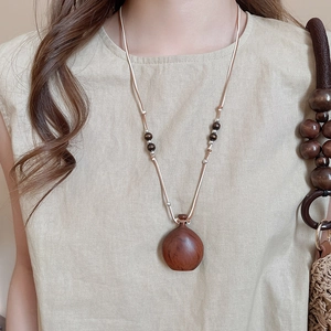 Close-up of a vintage wood flask pendant necklace with wax rope beads on a model