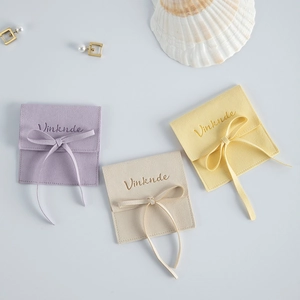 Elegant microfiber suede jewelry pouches in purple and beige with silk bow ribbons