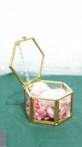 Macro detail of hexagonal gold metal frame glass jewelry box with pink and white flowers