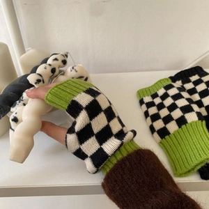 Detail of knitted arm warmers featuring a black and white checkerboard pattern with lime green trim