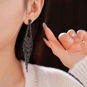 Close-up of elegant black tassel earrings with crystals worn by a model for evening style