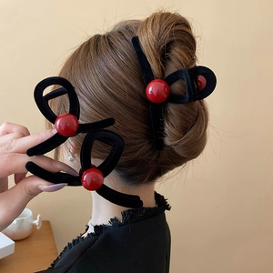 Detail of a black flocked bow hair claw clip featuring a glossy red bead accent