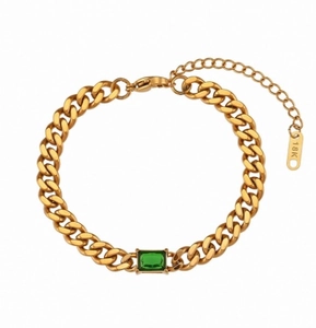 Dettaglio macro del bracciale a catena cubana dorata con zircone verde rettangolare