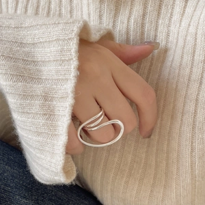 Detailed close-up of a silver twisted geometric ring worn on finger over cozy knitwear