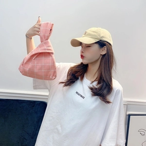 Close-up of pink and white checkered cotton wrist bag showing fabric texture and knot handle