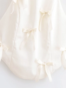 Detail of elegant satin fabric with scattered bow decorations in creamy white