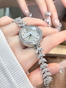 Detailed close-up of a silver watch with mother-of-pearl dial and crystal leaf-shaped band