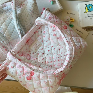 Detail von gesteppten Tragetaschen mit Blumen- und Kirschmuster, Textur und Innenetikett