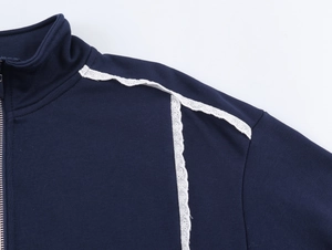Détail d'un pull en maille bleu marine avec dentelle blanche et fermeture éclair argent