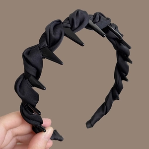 Detail view of black twisted fabric headband featuring inner plastic grip teeth for volume