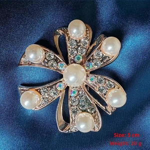 Detail shot of camellia brooch with rose gold finish and white pearls on blue silk