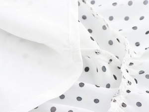 Vue macro détaillée du tissu en mousseline blanche à pois noirs avec couture fine