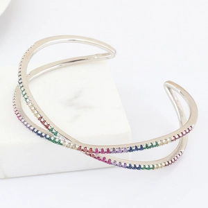 Detailed view of silver rainbow zircon crossover cuff bracelet on white marble