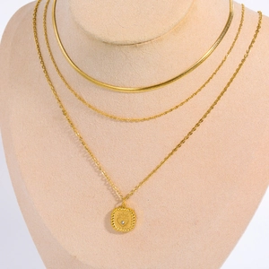 Detailed close-up of a triple-layered gold tarot necklace with a heart pendant on a model