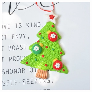 Macro detail of textured green polymer clay Christmas tree ornament with festive red ribbon