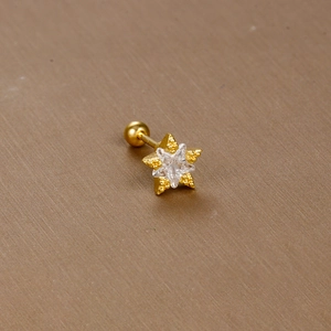 Macro detail of gold star stud earring with clear zircon and screw back ball closure