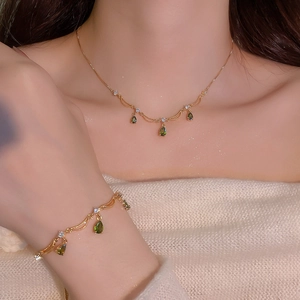 Elegante set di collana e bracciale placcato oro con pietre verdi a goccia su modella