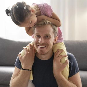Black matte beads bracelet with cross charm worn by a man holding a young child