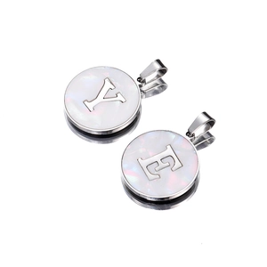 Detail of round stainless steel pendants with pearl inlay and cut-out letters Y and E
