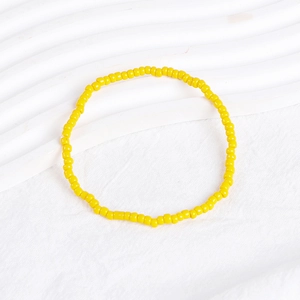 Close-up of yellow beaded bohemian bracelet on a white textured background