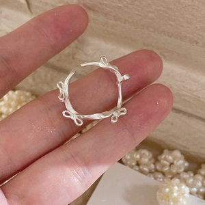 Détail d'une bague ouverte en argent en forme de branche avec petit nœud sur la main