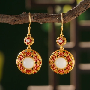 Macro detail of Chinese style gold earrings with red enamel and white jade pendant