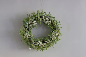 Close-up of artificial spring wreath with white berries and green leaves on rattan base