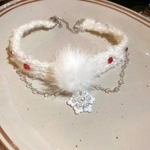 Détail du collier en fausse fourrure blanche avec gemme rouge, pompon doux et pendentif flocon