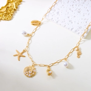Detailed view of golden marine necklace featuring starfish, shell, and pearl charms