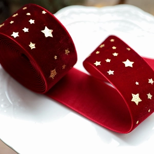 Red velvet Christmas ribbon with gold foil stars displayed on a ceramic plate