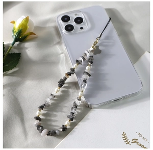 Détail d'un bijou de téléphone en pierres naturelles et perles blanches sur une coque