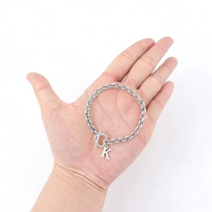 Silver heart buckle chain bracelet with letter K pendant held in hand on white background