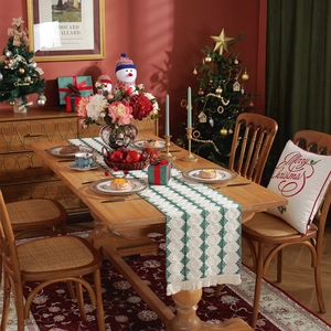 Christmas striped table runner with green diamond pattern and red tassels on dining table