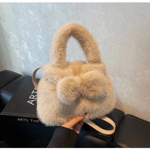 Detailed close-up of beige plush bucket bag with decorative bow and textured fur