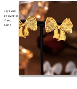 Detail of gold bow earrings featuring a brushed metal texture on a jewelry display
