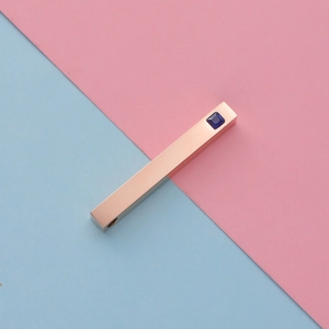 Macro shot of rose gold rectangular pendant with blue gem on pink and blue background