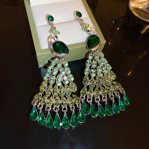 Detail of green crystal peacock tassel earrings with silver needles on jewelry box
